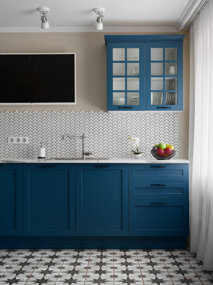 Transitional l-shaped kitchen in Other with glass-front cabinets, blue cabinets, solid surface benchtops, white splashback, ceramic splashback, ceramic floors and white benchtop.