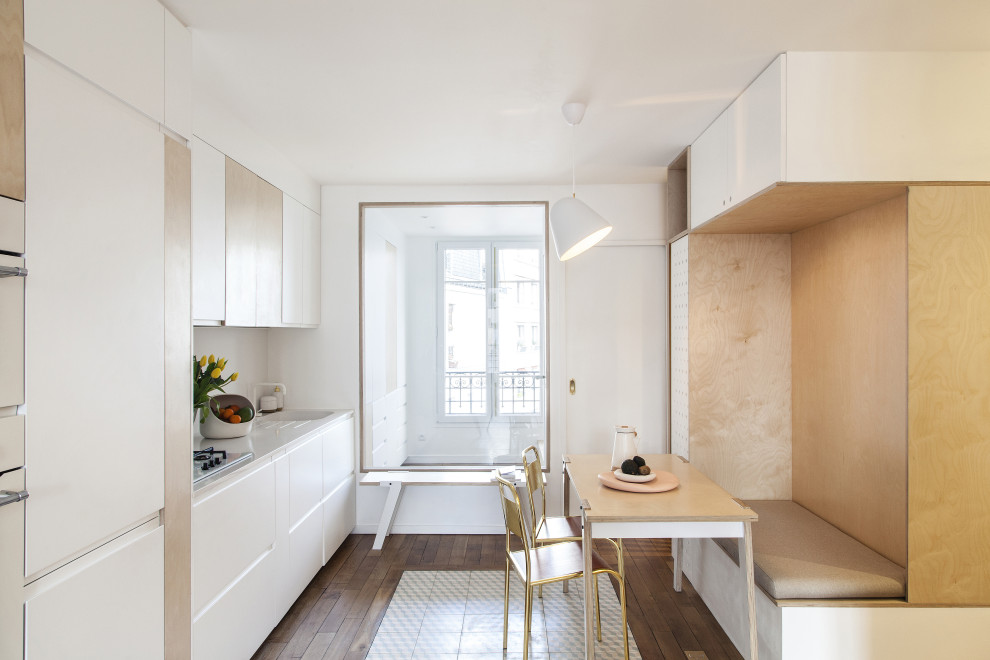 Bild på ett mellanstort minimalistiskt vit linjärt vitt kök och matrum, med en integrerad diskho, släta luckor, vita skåp, bänkskiva i kvartsit, vitt stänkskydd, integrerade vitvaror, mellanmörkt trägolv och brunt golv