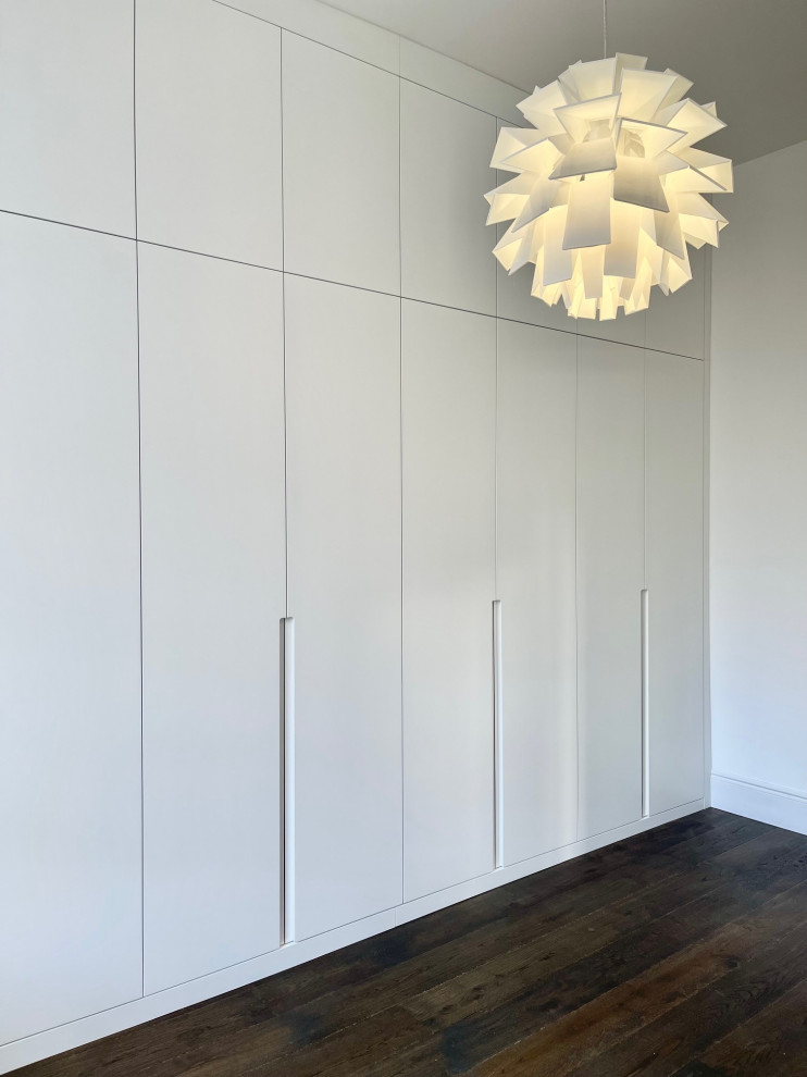 Idée de décoration pour une armoire encastrée design de taille moyenne avec un sol marron.