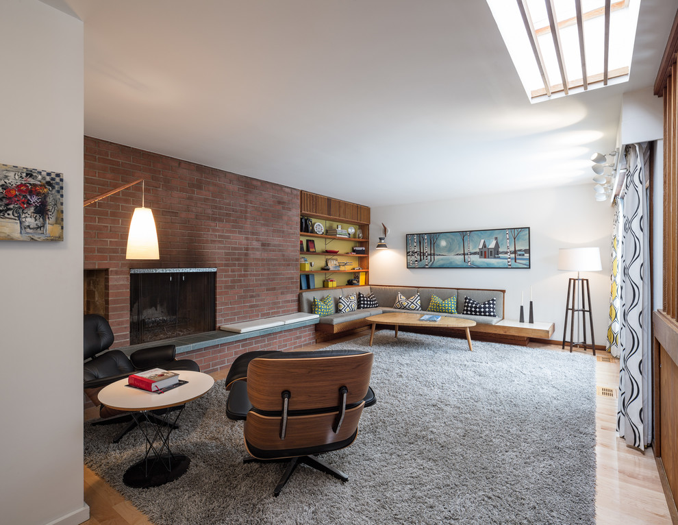 Inspiration for a large midcentury open concept living room in Ottawa with a library, white walls, carpet, a standard fireplace, a brick fireplace surround and no tv.
