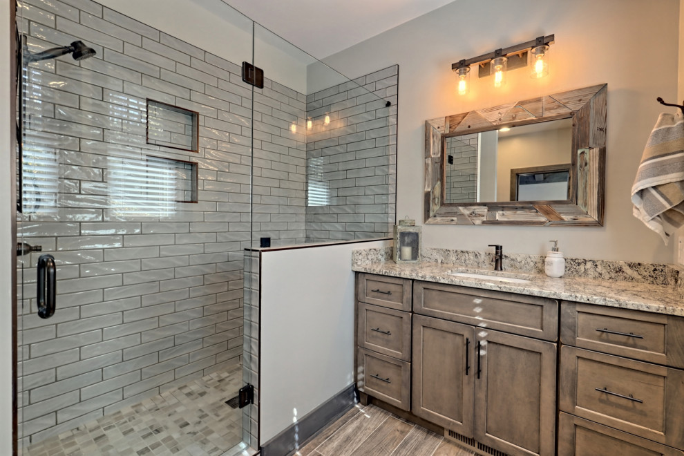 This is an example of a medium sized classic shower room bathroom in Atlanta with shaker cabinets, medium wood cabinets, an alcove shower, a two-piece toilet, grey tiles, metro tiles, grey walls, ceramic flooring, a submerged sink, granite worktops, brown floors, a hinged door, brown worktops, a wall niche, a single sink and a built in vanity unit.