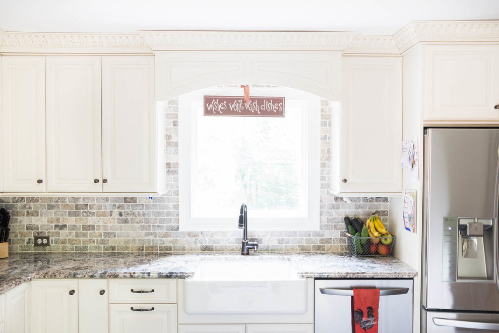This is an example of a small country l-shaped eat-in kitchen in Philadelphia with a farmhouse sink, raised-panel cabinets, white cabinets, granite benchtops, multi-coloured splashback, stone tile splashback, stainless steel appliances, cement tiles, with island and grey floor.