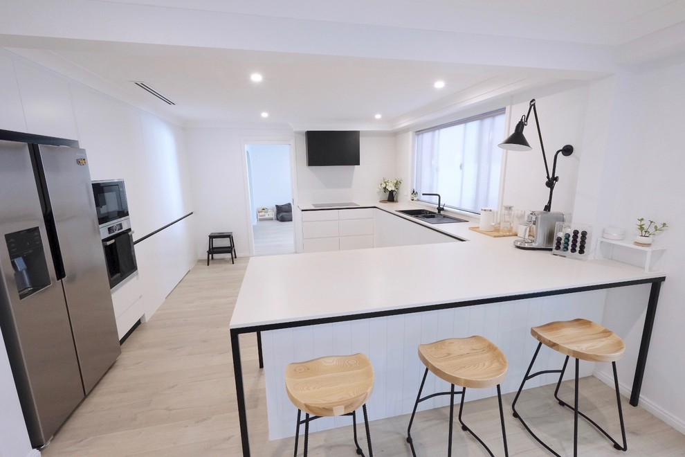 Design ideas for a mid-sized modern u-shaped eat-in kitchen in Sydney with a drop-in sink, quartz benchtops, white splashback, mosaic tile splashback, stainless steel appliances, laminate floors, with island, beige floor and white benchtop.