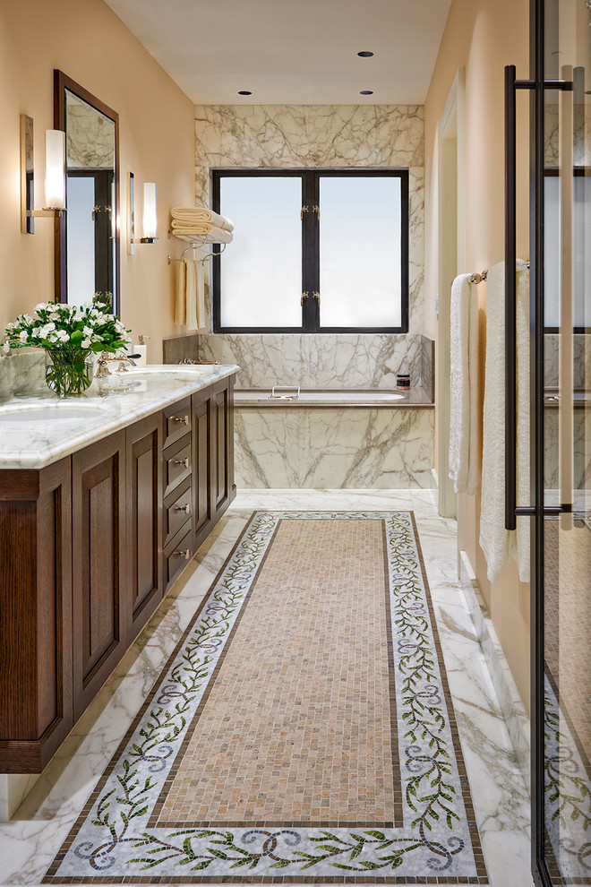 Design ideas for a large mediterranean master bathroom in San Francisco with raised-panel cabinets, medium wood cabinets, a drop-in tub, an alcove shower, white tile, marble, beige walls, marble floors, an undermount sink, marble benchtops, white floor, a hinged shower door and white benchtops.