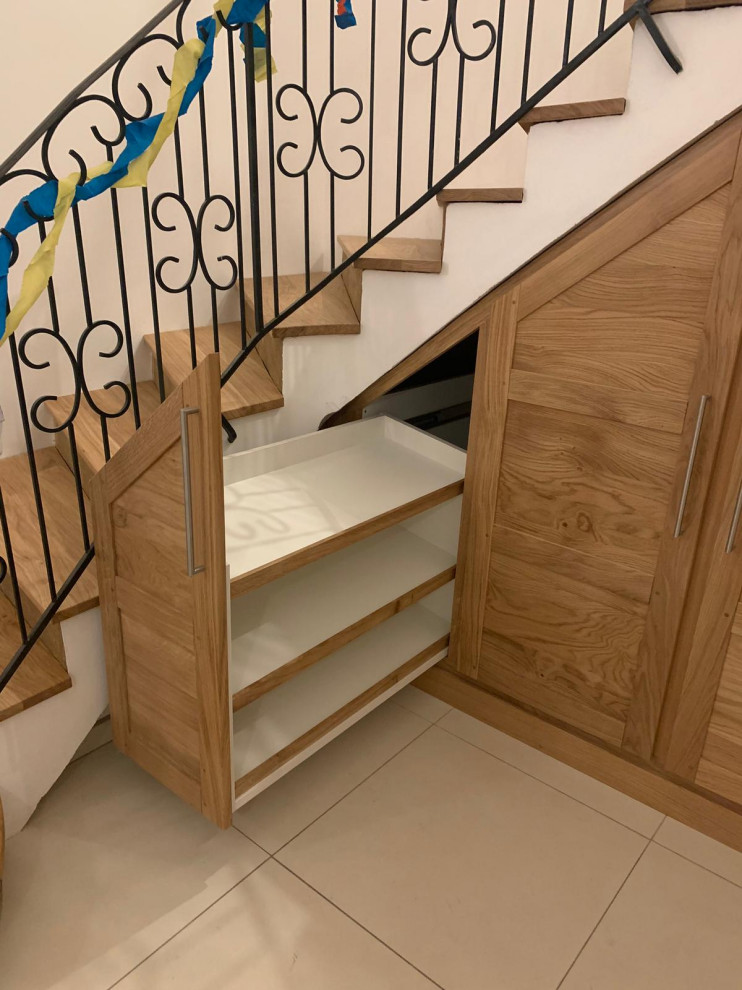 Идея дизайна: большая изогнутая деревянная лестница в стиле кантри с деревянными ступенями, металлическими перилами и кладовкой или шкафом под ней