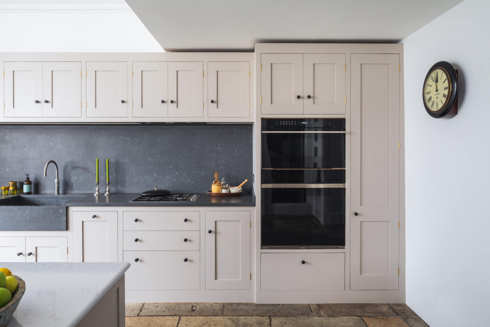 This is an example of a large traditional galley open plan kitchen in London with shaker cabinets, quartzite benchtops, with island and grey benchtop.