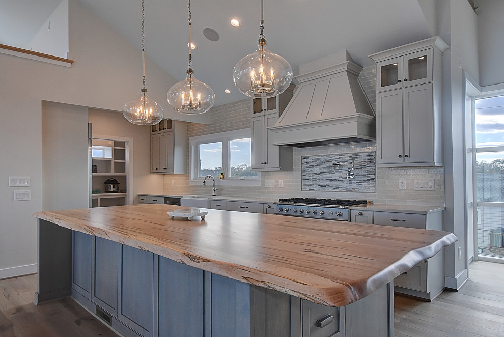 Inspiration for a small beach style separate kitchen in DC Metro with a farmhouse sink, flat-panel cabinets, wood benchtops, subway tile splashback, stainless steel appliances, light hardwood floors, with island, beige floor, beige benchtop and wood.
