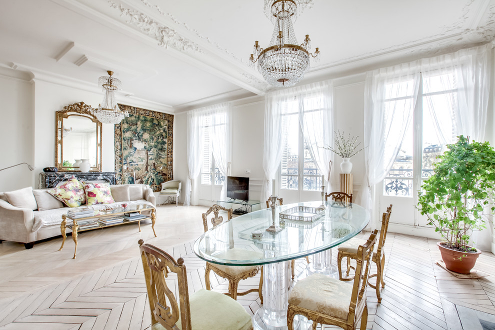 This is an example of a traditional open plan dining in Paris with white walls, light hardwood floors, a standard fireplace, a stone fireplace surround and beige floor.