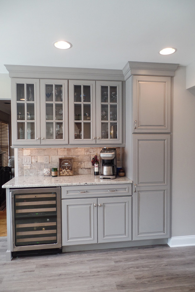 This is an example of a small traditional single-wall home bar in Philadelphia with no sink, raised-panel cabinets, grey cabinets, granite benchtops, multi-coloured splashback, ceramic splashback and vinyl floors.