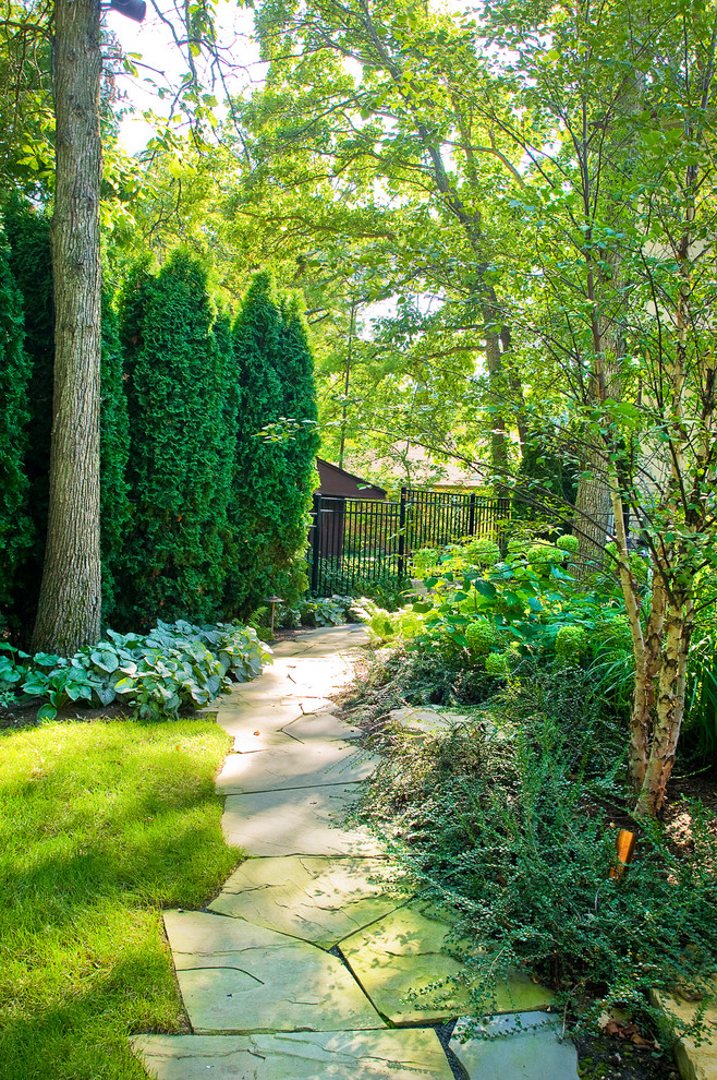 Traditional backyard shaded garden in Chicago with natural stone pavers.