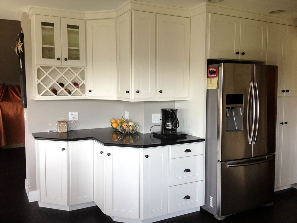 Example of a large transitional l-shaped dark wood floor and black floor open concept kitchen design with a farmhouse sink, shaker cabinets, white cabinets, quartz countertops, stainless steel appliances and an island