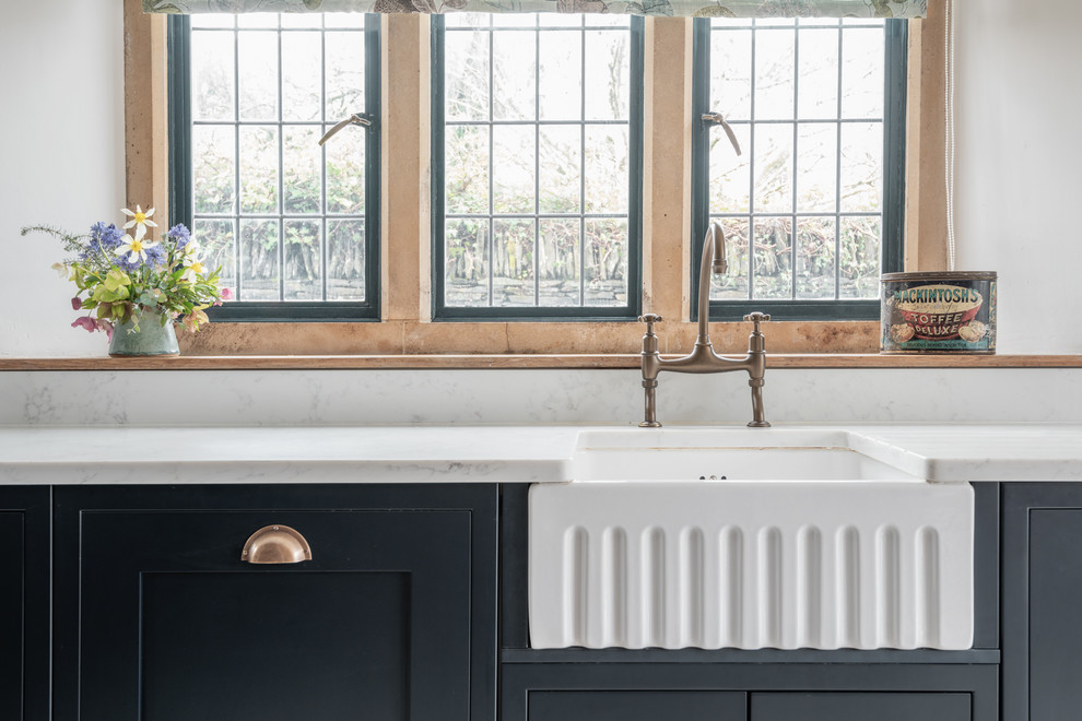 Inspiration for a medium sized traditional u-shaped kitchen/diner in Devon with a belfast sink, shaker cabinets, blue cabinets, composite countertops, limestone flooring, no island and white worktops.