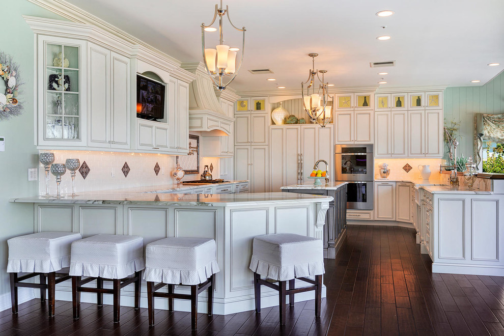 Large traditional u-shaped eat-in kitchen in New York with a farmhouse sink, recessed-panel cabinets, grey cabinets, marble benchtops, white splashback, ceramic splashback, panelled appliances, plywood floors and with island.