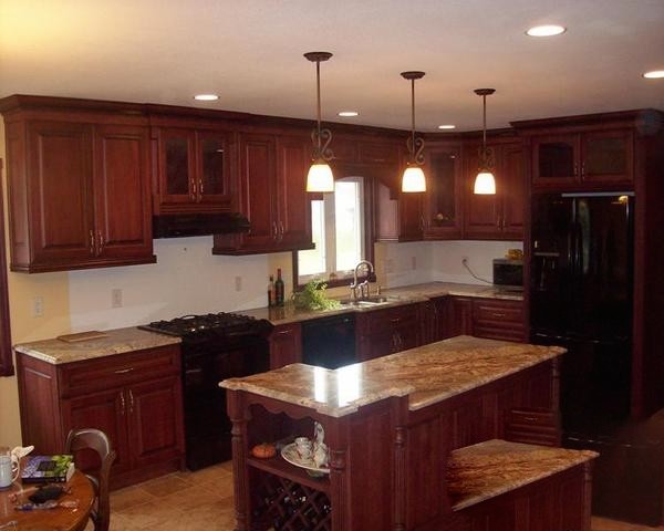 Inspiration for a large galley light wood floor enclosed kitchen remodel in Cedar Rapids with a drop-in sink, raised-panel cabinets, medium tone wood cabinets, black appliances and an island