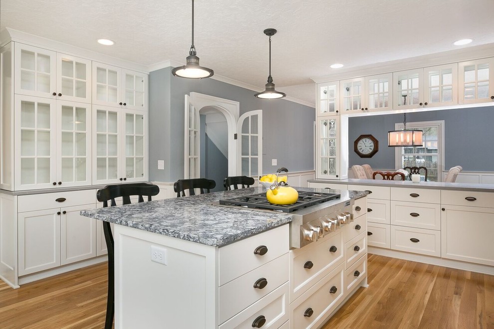 Inspiration for a mid-sized traditional u-shaped eat-in kitchen in Portland with a farmhouse sink, flat-panel cabinets, white cabinets, quartzite benchtops, white splashback, subway tile splashback, stainless steel appliances, medium hardwood floors and with island.