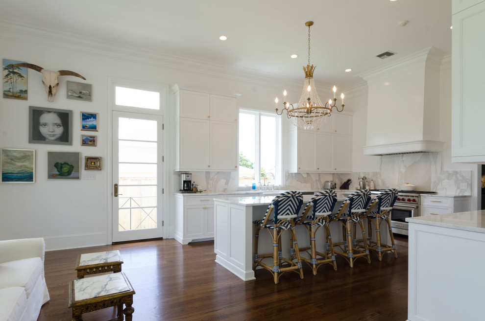Inspiration for a mid-sized beach style u-shaped kitchen in New Orleans with an undermount sink, raised-panel cabinets, white cabinets, marble benchtops, white splashback, stainless steel appliances, dark hardwood floors and with island.
