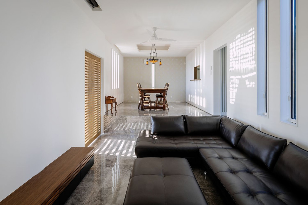 Пример оригинального дизайна: огромная гостиная комната с белыми стенами, полом из керамической плитки, отдельно стоящим телевизором, серым полом, потолком с обоями и обоями на стенах без камина