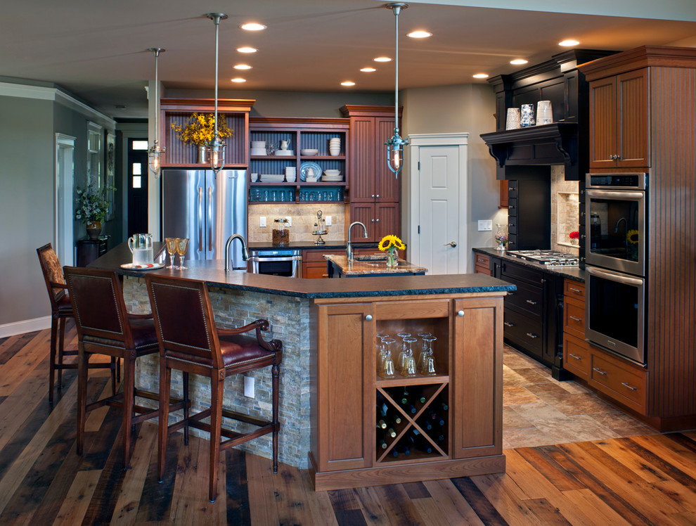 Design ideas for a country l-shaped eat-in kitchen in Charlotte with dark wood cabinets, soapstone benchtops, beige splashback, stone tile splashback, stainless steel appliances, medium hardwood floors and with island.