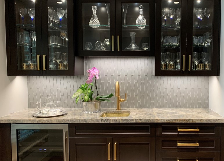 This is an example of a small modern single-wall wet bar in Houston with an undermount sink, glass-front cabinets, dark wood cabinets, quartzite benchtops, grey splashback, light hardwood floors, brown floor, blue benchtop and glass tile splashback.