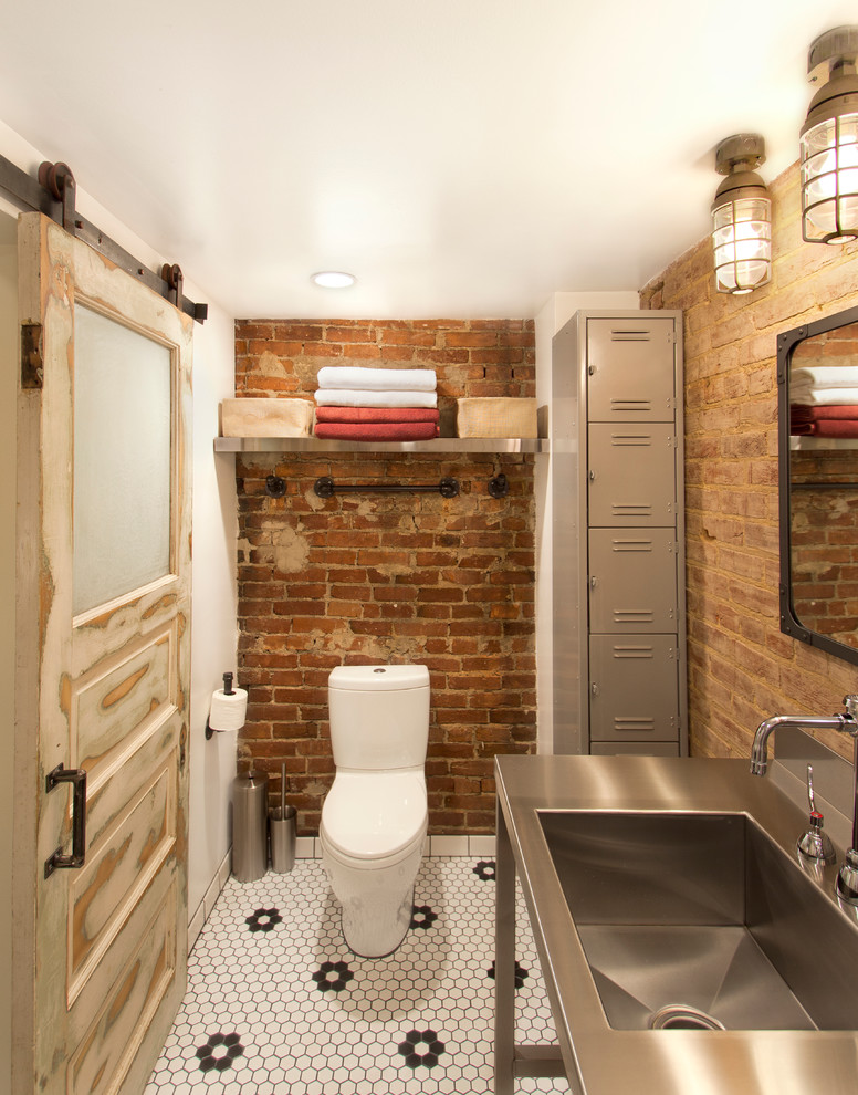 This is an example of an industrial powder room in DC Metro with stainless steel benchtops, a two-piece toilet, mosaic tile floors, an integrated sink and black and white tile.