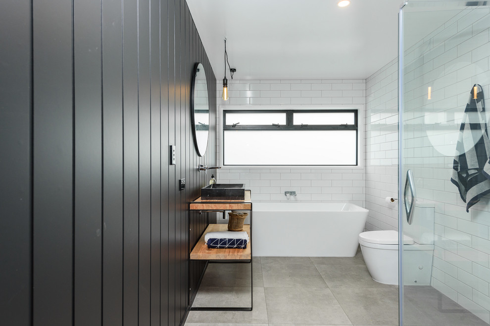 Inspiration for a contemporary 3/4 bathroom in Hamilton with open cabinets, medium wood cabinets, a freestanding tub, a corner shower, white tile, subway tile, black walls, a vessel sink, wood benchtops, grey floor and brown benchtops.