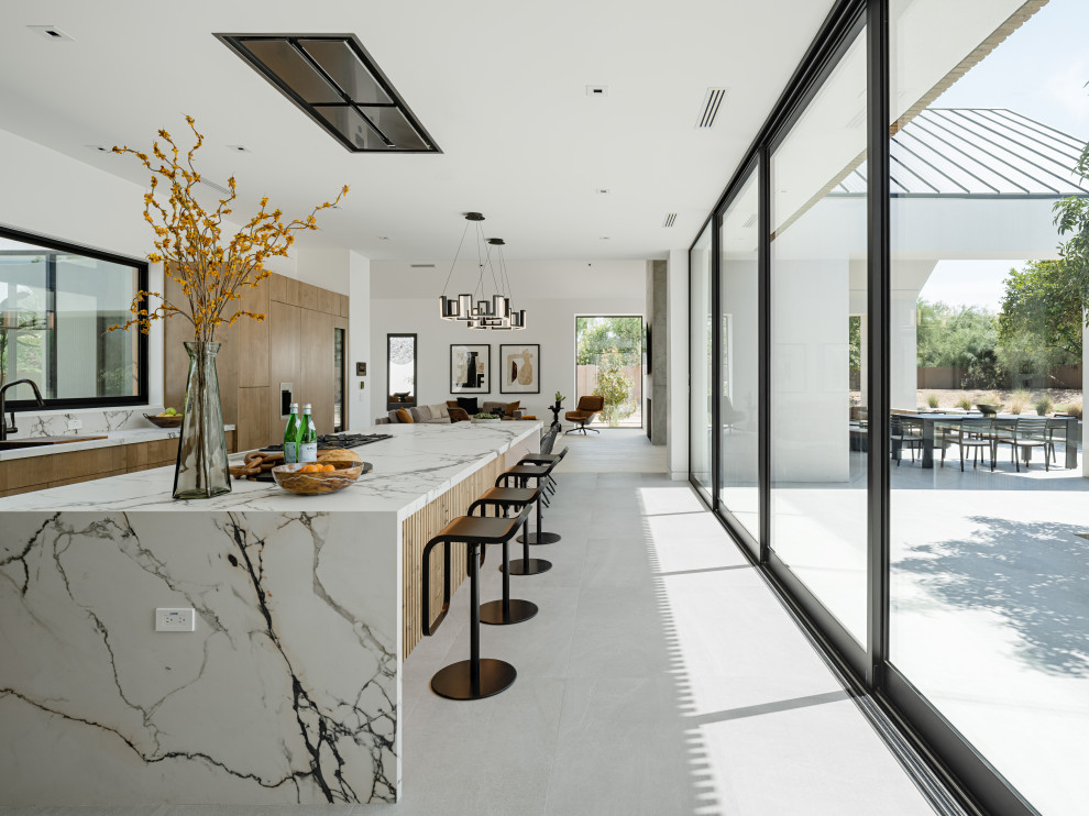 Inspiration for a modern l-shaped eat-in kitchen in Phoenix with a double-bowl sink, flat-panel cabinets, medium wood cabinets, quartz benchtops, engineered quartz splashback, panelled appliances, porcelain floors, with island and grey floor.