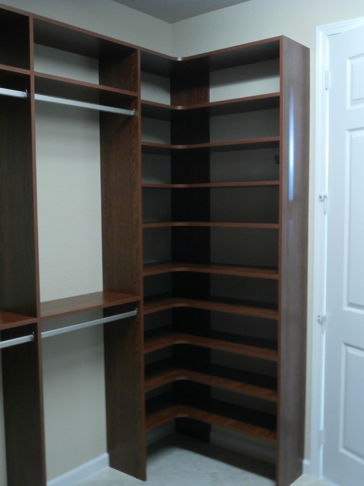 Mid-sized traditional gender-neutral walk-in wardrobe in Orlando with open cabinets, dark wood cabinets, carpet and beige floor.