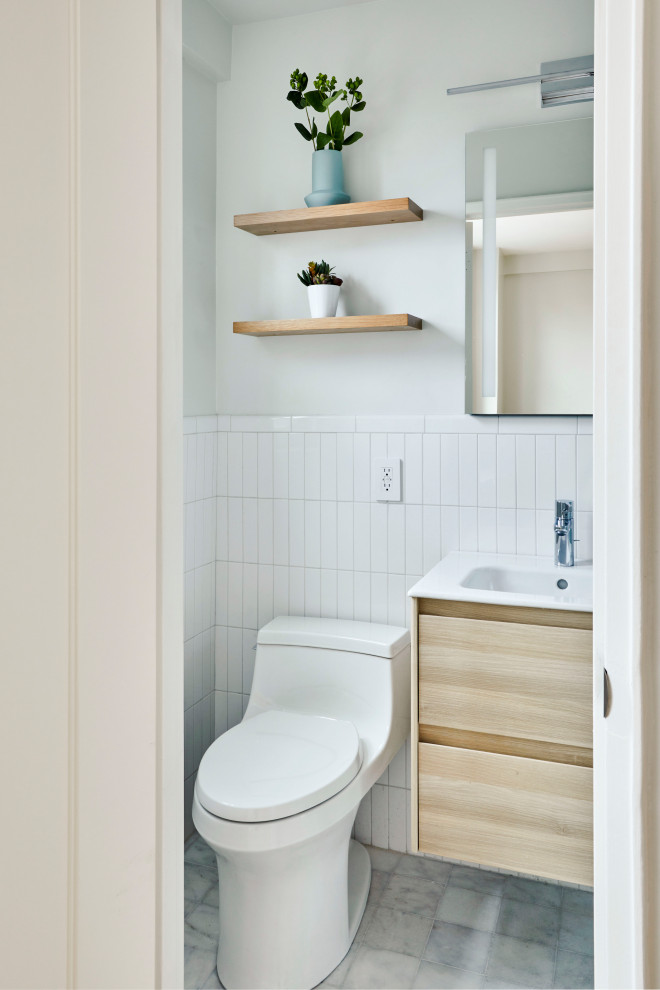На фото: маленькая главная ванная комната в современном стиле с плоскими фасадами, светлыми деревянными фасадами, душем в нише, унитазом-моноблоком, белой плиткой, керамической плиткой, серыми стенами, мраморным полом, монолитной раковиной, столешницей из искусственного камня, серым полом, душем с раздвижными дверями, белой столешницей, нишей, тумбой под одну раковину, подвесной тумбой и многоуровневым потолком для на участке и в саду с