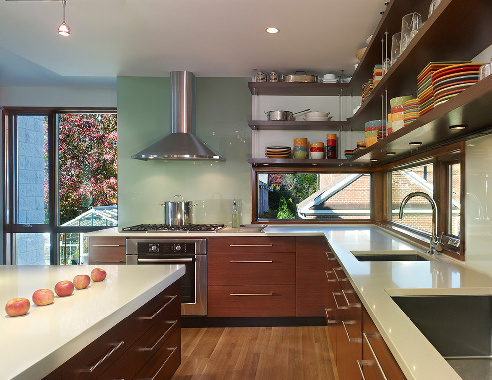 Inspiration for a mid-sized modern l-shaped open plan kitchen in DC Metro with a single-bowl sink, glass sheet splashback, green splashback, flat-panel cabinets, medium wood cabinets, stainless steel appliances, medium hardwood floors and with island.