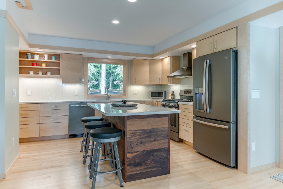 Example of a mid-sized mountain style l-shaped light wood floor open concept kitchen design with a double-bowl sink, flat-panel cabinets, light wood cabinets, quartz countertops, beige backsplash, glass sheet backsplash, stainless steel appliances, an island and white countertops
