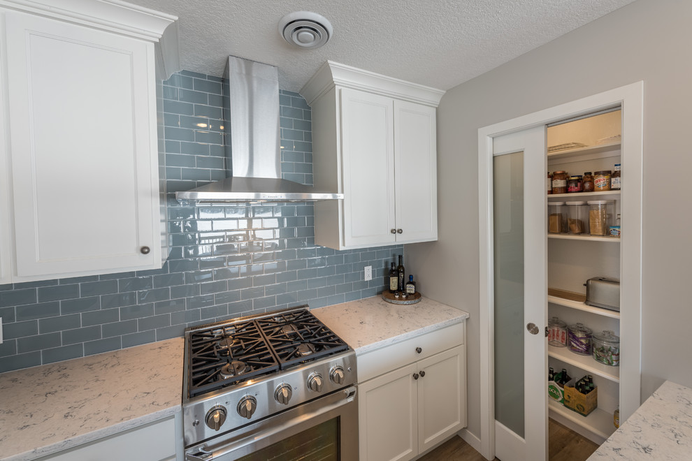 Small transitional u-shaped eat-in kitchen in Minneapolis with an undermount sink, shaker cabinets, white cabinets, quartzite benchtops, grey splashback, subway tile splashback, stainless steel appliances, light hardwood floors, a peninsula, beige floor and white benchtop.