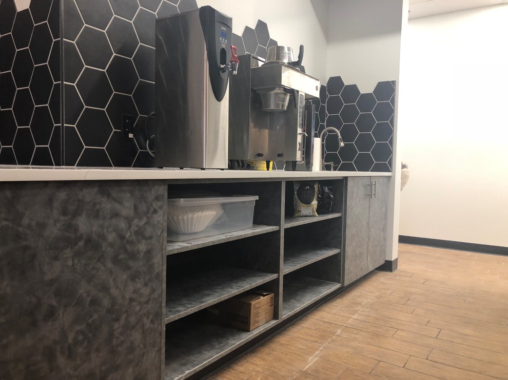 Photo of a large industrial l-shaped seated home bar in Omaha with a drop-in sink, open cabinets, grey cabinets, onyx benchtops, black splashback, ceramic splashback, ceramic floors, brown floor and white benchtop.