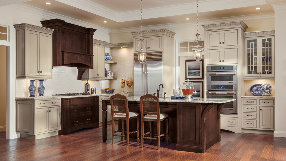 This is an example of a traditional l-shaped kitchen in Other with an undermount sink, beaded inset cabinets, quartzite benchtops, white splashback, with island, beige cabinets, stainless steel appliances and dark hardwood floors.
