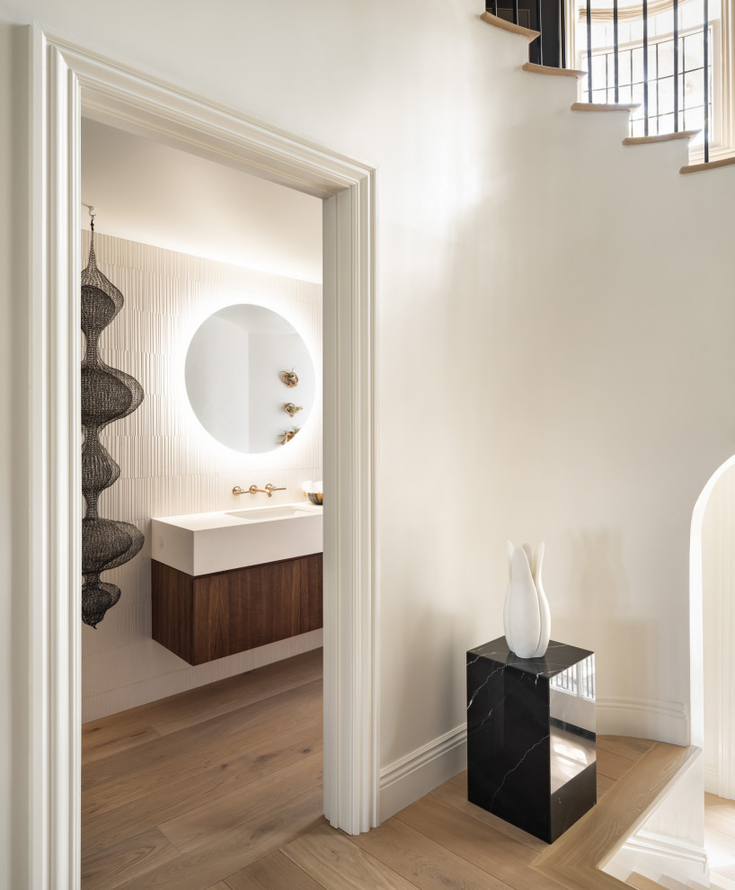 Inspiration for a mid-sized modern powder room in San Francisco with flat-panel cabinets, medium wood cabinets, a wall-mount toilet, white tile, limestone, white walls, light hardwood floors, an undermount sink, limestone benchtops, beige floor, white benchtops and a floating vanity.