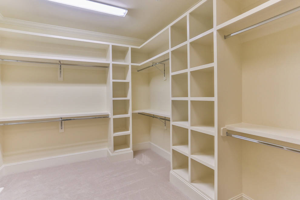 This is an example of a mid-sized mediterranean gender-neutral walk-in wardrobe in Raleigh with open cabinets, white cabinets, carpet and beige floor.