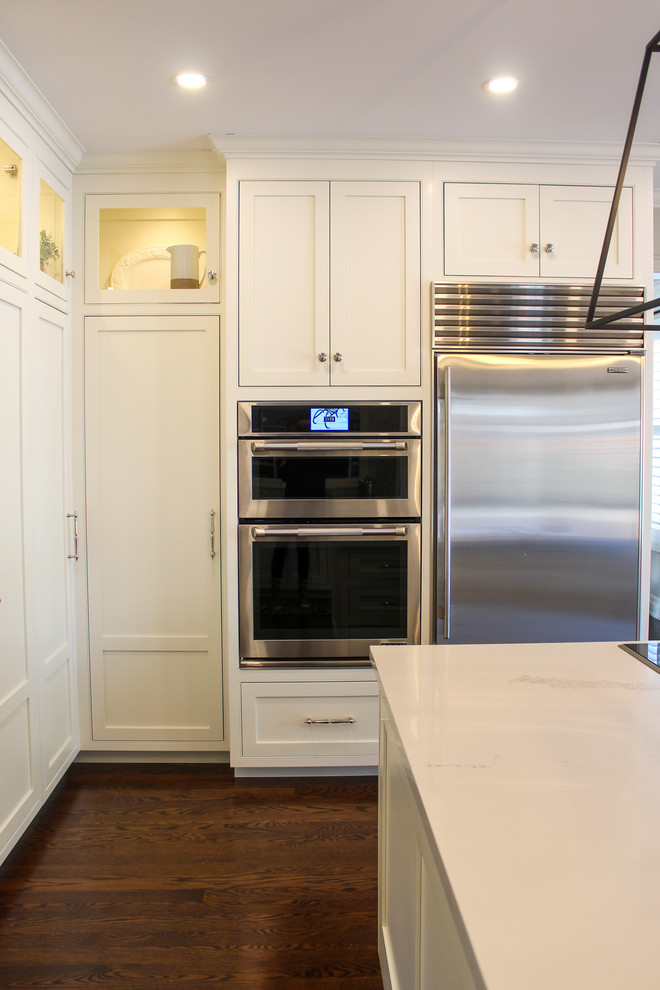 Example of a mid-sized transitional u-shaped dark wood floor and brown floor eat-in kitchen design in Toronto with an undermount sink, shaker cabinets, white cabinets, quartzite countertops, multicolored backsplash, mosaic tile backsplash, stainless steel appliances, an island and white countertops