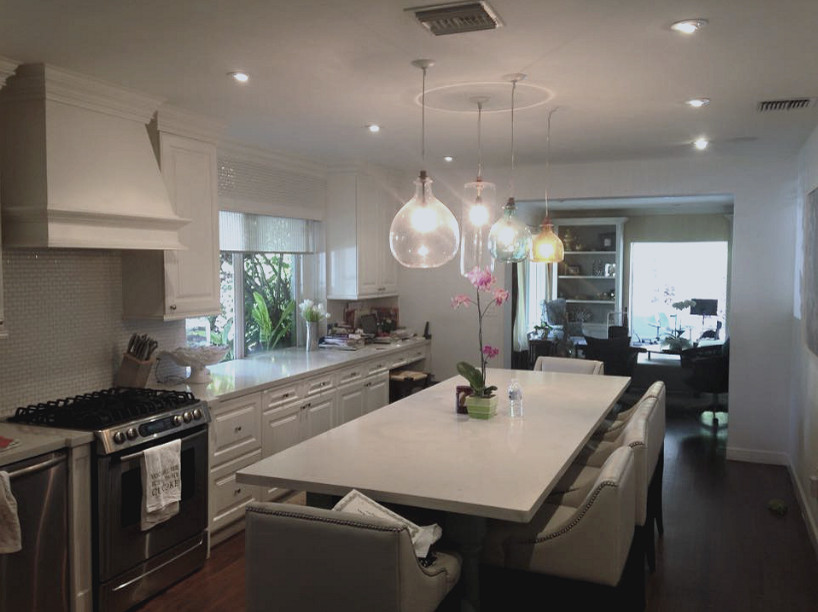 Mid-sized transitional single-wall dark wood floor enclosed kitchen photo in Miami with raised-panel cabinets, white cabinets, quartz countertops, white backsplash, ceramic backsplash, stainless steel appliances and an island
