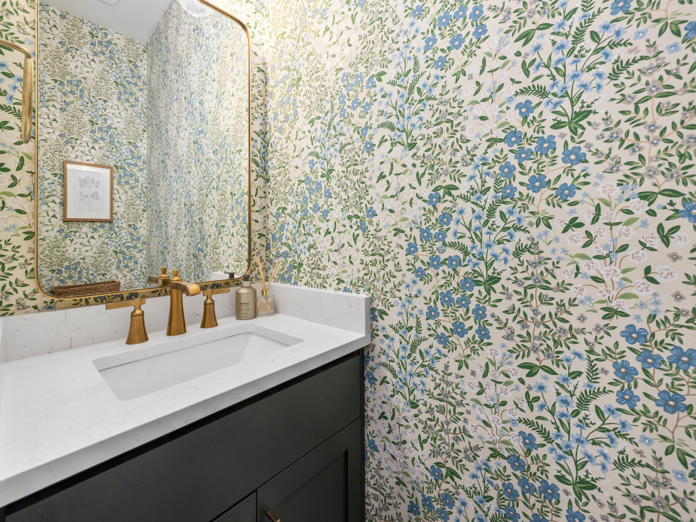 Immagine di una piccola stanza da bagno classica con ante in stile shaker, ante verdi, pareti blu, top in quarzo composito, top bianco, toilette, un lavabo, mobile bagno incassato e carta da parati