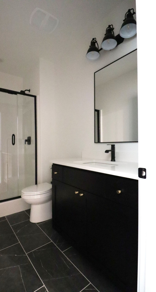 Aménagement d'une salle de bain campagne avec un placard à porte shaker, des portes de placard noires, un mur blanc, un sol en carrelage de porcelaine, un lavabo encastré, un plan de toilette en quartz modifié, un sol noir, une cabine de douche à porte battante, un plan de toilette blanc, un banc de douche, meuble simple vasque et meuble-lavabo encastré.