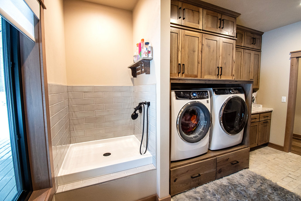 Inspiration for a large rustic ceramic tile and multicolored floor laundry room remodel with flat-panel cabinets, brown cabinets, granite countertops, beige walls and white countertops