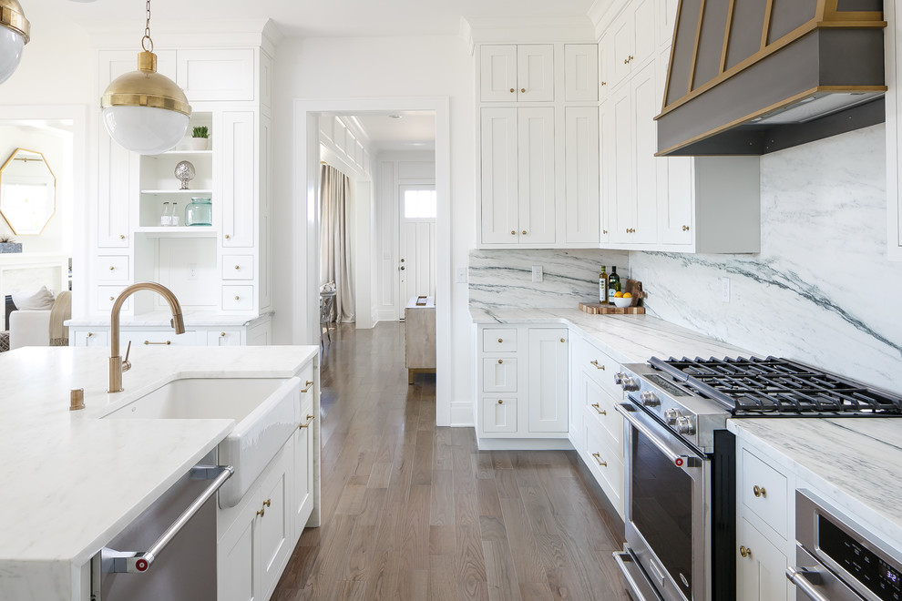 Inspiration for a large transitional l-shaped eat-in kitchen in Louisville with a farmhouse sink, beaded inset cabinets, white cabinets, marble benchtops, white splashback, stone slab splashback, stainless steel appliances, medium hardwood floors and with island.