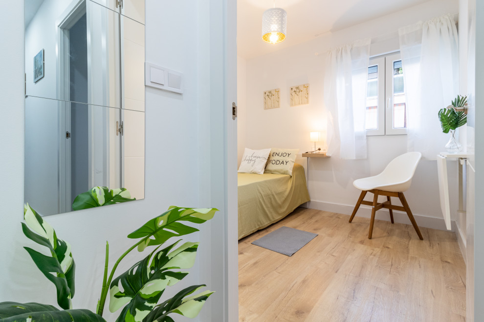 Foto de habitación de invitados blanca y madera nórdica con paredes blancas, suelo de madera clara y suelo marrón