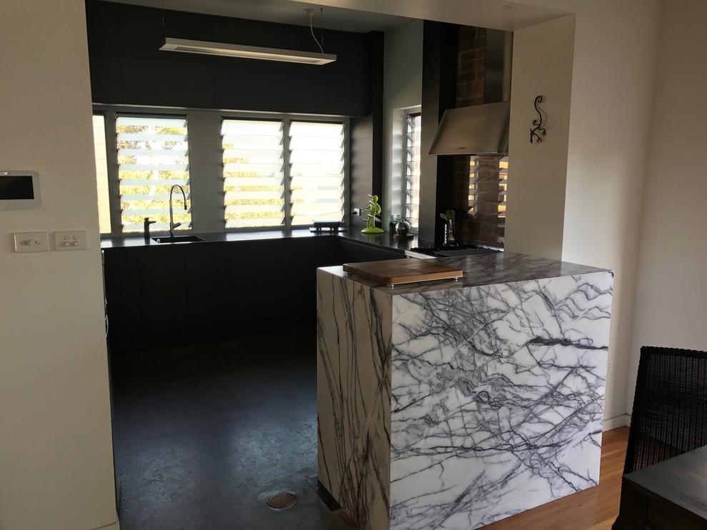 Mid-sized industrial kitchen in Newcastle - Maitland with an undermount sink, marble benchtops, glass sheet splashback, concrete floors and with island.