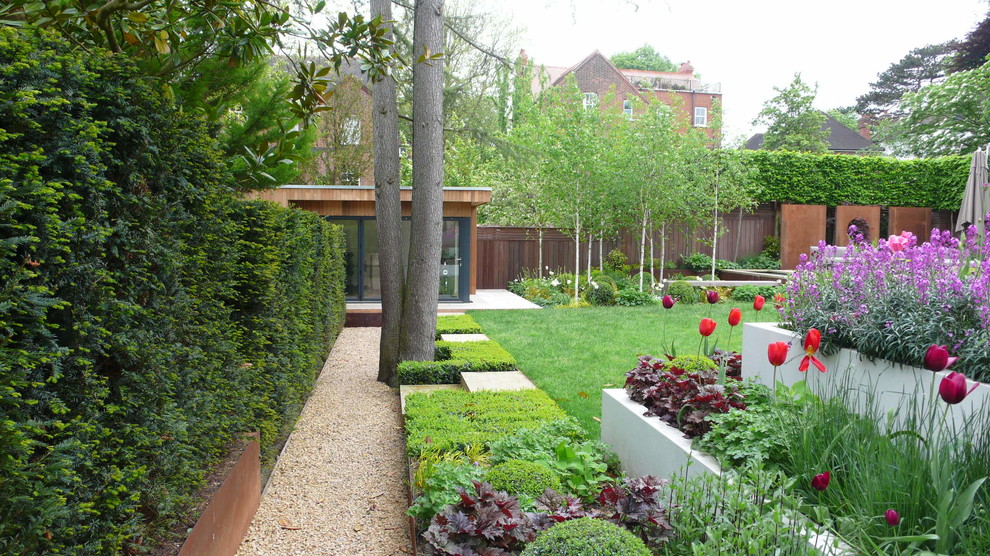 Design ideas for a large contemporary backyard partial sun formal garden in London with gravel and with raised garden bed.