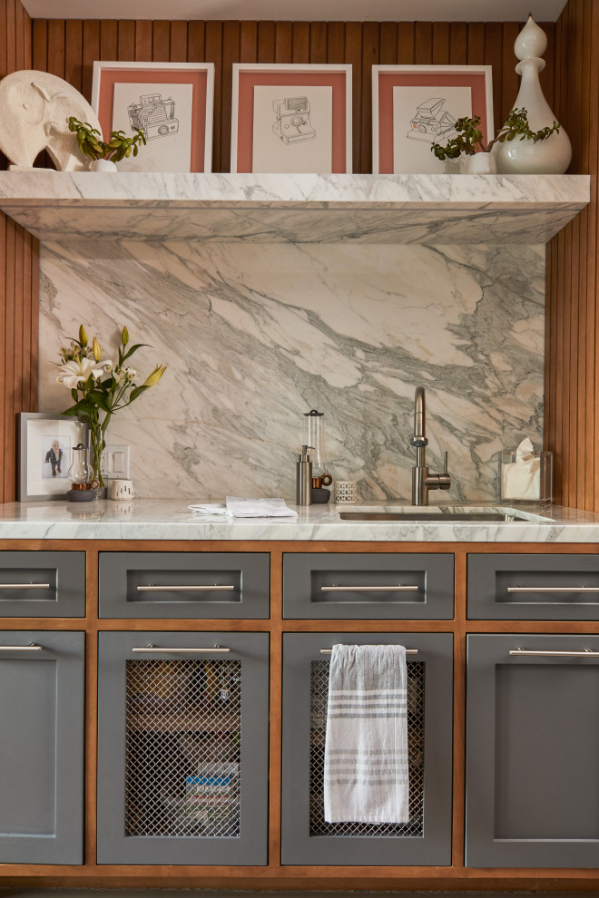 This is an example of a mid-sized midcentury galley utility room in Los Angeles with an undermount sink, shaker cabinets, grey cabinets, marble benchtops, white walls, concrete floors, a concealed washer and dryer, grey floor and white benchtop.