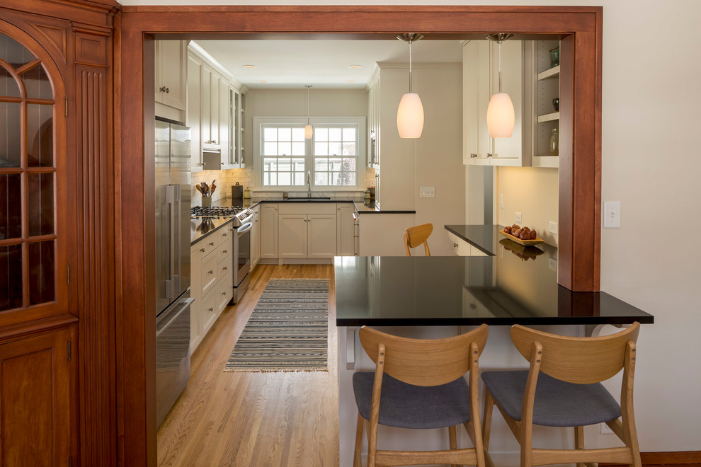 Kitchen - mid-sized transitional galley medium tone wood floor and brown floor kitchen idea in Minneapolis with a single-bowl sink, shaker cabinets, quartz countertops, gray backsplash, marble backsplash, stainless steel appliances, a peninsula and black countertops