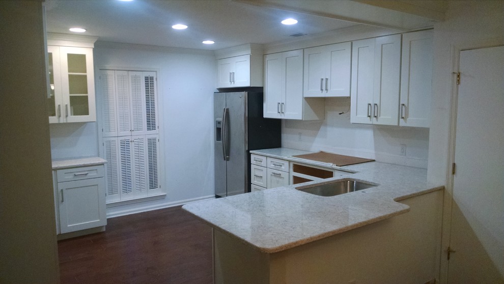 Open concept kitchen - mid-sized transitional u-shaped medium tone wood floor open concept kitchen idea with a drop-in sink, shaker cabinets, white cabinets, quartzite countertops, stainless steel appliances and a peninsula