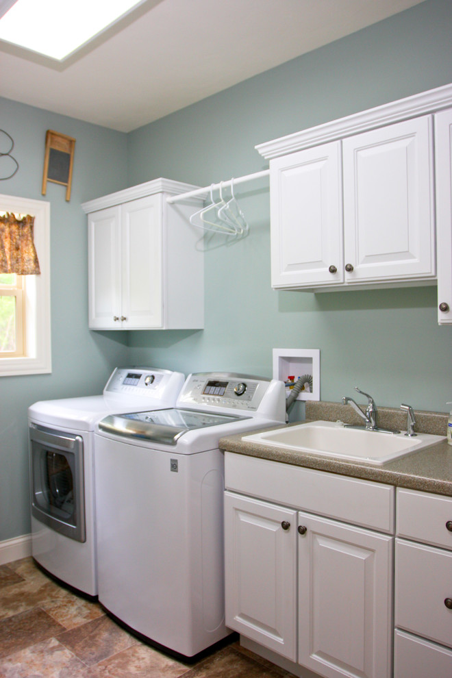 Photo of a mid-sized traditional single-wall dedicated laundry room in Milwaukee with raised-panel cabinets, white cabinets, laminate benchtops, linoleum floors, a side-by-side washer and dryer, a drop-in sink and blue walls.