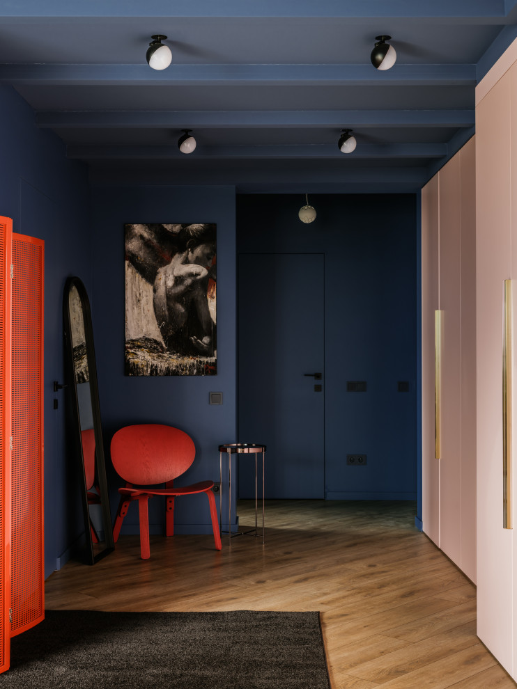 Design ideas for a large eclectic entry hall in Moscow with blue walls, medium hardwood floors, a single front door, a blue front door, brown floor, vaulted and brick walls.