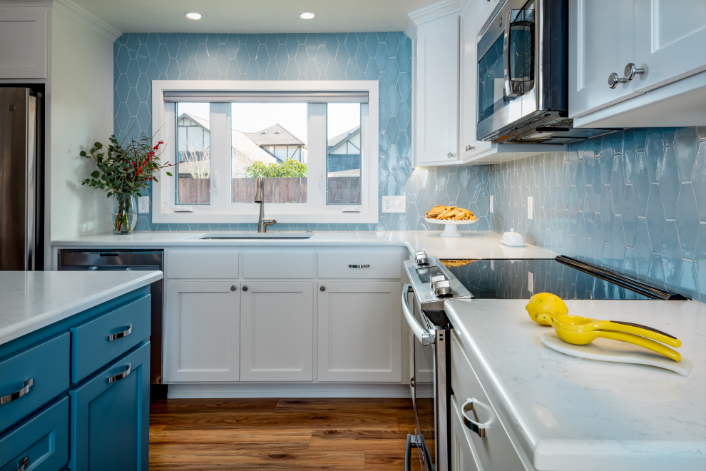 Immagine di una cucina stile americano di medie dimensioni con lavello sottopiano, ante in stile shaker, ante bianche, top in quarzite, paraspruzzi blu, paraspruzzi con piastrelle in ceramica, elettrodomestici in acciaio inossidabile, pavimento in laminato e top bianco